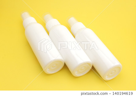 Three white spray bottles stand neatly against a vibrant yellow backdrop. Minimalist design suggests versatility for skincare or cleaning applications. Clean surfaces imply hygiene and simplicity Three white spray bottles stand neatly against a vibrant yellow backdrop. Minimalist design suggests versatility for skincare or cleaning applications. Clean surfaces imply hygiene and simplicity 140194619
