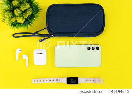 Minimalist tech setup on bright yellow background. Modern smartphone, smartwatch, earbuds, and case neatly arranged. Clean aesthetic suits lifestyle, wellness, or tech-focused content Minimalist tech setup on bright yellow background. Modern smartphone, smartwatch, earbuds, and case neatly arranged. Clean aesthetic suits lifestyle, wellness, or tech-focused content 140194640