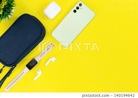 Minimalist tech setup on bright yellow background. Modern smartphone, smartwatch, earbuds, and case neatly arranged. Clean aesthetic suits lifestyle, wellness, or tech-focused content Minimalist tech setup on bright yellow background. Modern smartphone, smartwatch, earbuds, and case neatly arranged. Clean aesthetic suits lifestyle, wellness, or tech-focused content 140194642