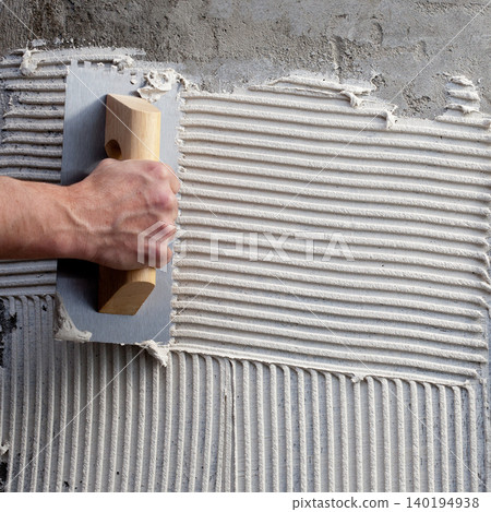 construction notched trowel with white cement 140194938
