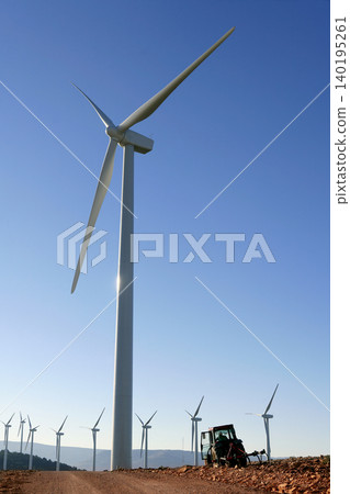 Agriculture tractor under electric wind mills in blue sky Agriculture tractor under electric wind mills in blue sky 140195261