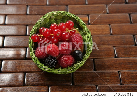 Mixed berries in a green little basket Mixed berries in a green little basket 140195815