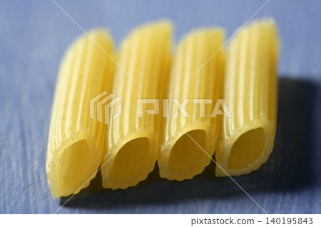 Four yellow macaroni in a line, macro in blue background 140195843