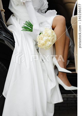 Bride getting out of car holding white roses bouquet 140196077