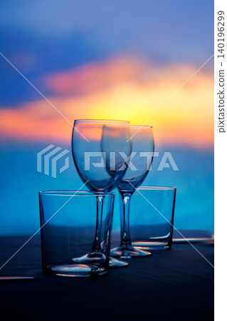 Dish of cups and crystal glasses on sea sunset Dish of cups and crystal glasses on sea sunset 140196299