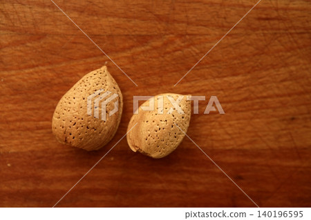 Two almond nuts on a golden wood table Two almond nuts on a golden wood table 140196595