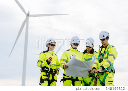 Group of professional engineer team standing meeting with plan for wind turbine construction. Group of professional engineer team standing meeting with plan for wind turbine construction. 140196812