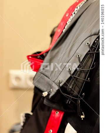 Closeup view of hanging leather garments, black leather piece with red accents. Bright stitching and lacing details, craftsmanship. Decorative for design about making garment Closeup view of hanging leather garments, black leather piece with red accents. Bright stitching and lacing details, craftsmanship. Decorative for design about making garment 140196855