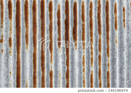 Weathered metal sheet shows vertical ridges and rust streaks 140196974
