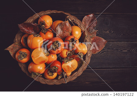 fresh persimmon in a basket, with leaves, top view, no people, 140197122