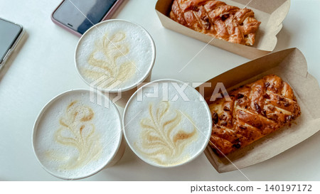 Cozy breakfast flat lay with three latte art coffees and sweet danish pastries in boxes Cozy breakfast flat lay with three latte art coffees and sweet danish pastries in boxes 140197172