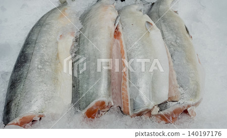 Fresh raw salmon carcasses chilled on crushed ice at a fish market counter Fresh raw salmon carcasses chilled on crushed ice at a fish market counter 140197176