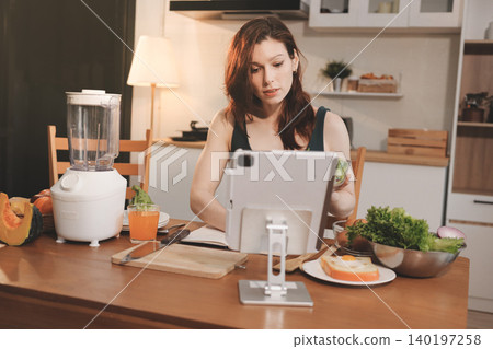 Woman preparing green smoothie in bright kitchen with fresh fruits and vegetables, healthy eating lifestyle moment in natural daylight Woman preparing green smoothie in bright kitchen with fresh fruits and vegetables, healthy eating lifestyle moment in natural daylight 140197258