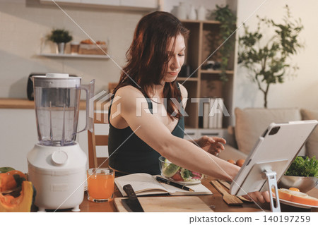Woman preparing green smoothie in bright kitchen with fresh fruits and vegetables, healthy eating lifestyle moment in natural daylight Woman preparing green smoothie in bright kitchen with fresh fruits and vegetables, healthy eating lifestyle moment in natural daylight 140197259