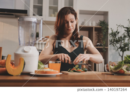 Woman preparing green smoothie in bright kitchen with fresh fruits and vegetables, healthy eating lifestyle moment in natural daylight Woman preparing green smoothie in bright kitchen with fresh fruits and vegetables, healthy eating lifestyle moment in natural daylight 140197264