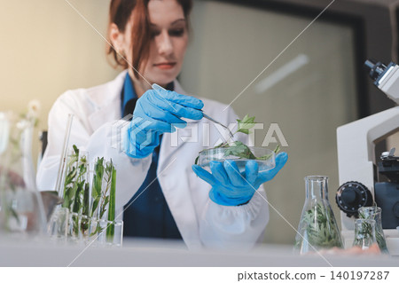 Scientists in lab coats work with plants in a modern lab, focusing on research and experimentation under bright, sterile conditions. Scientists in lab coats work with plants in a modern lab, focusing on research and experimentation under bright, sterile conditions. 140197287