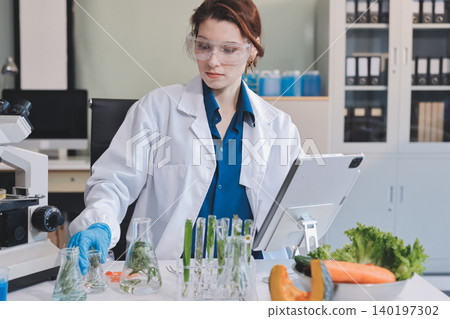 Scientists in lab coats work with plants in a modern lab, focusing on research and experimentation under bright, sterile conditions. Scientists in lab coats work with plants in a modern lab, focusing on research and experimentation under bright, sterile conditions. 140197302