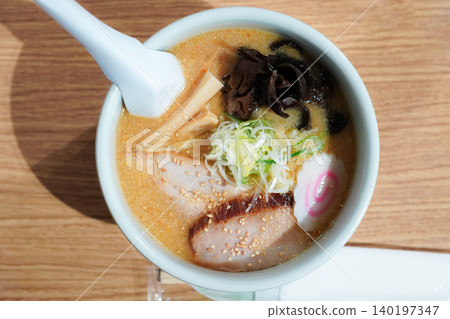 A delicious-looking tonkotsu miso ramen topped with char siu pork and green onions (overhead view). A delicious-looking tonkotsu miso ramen topped with char siu pork and green onions (overhead view). 140197347