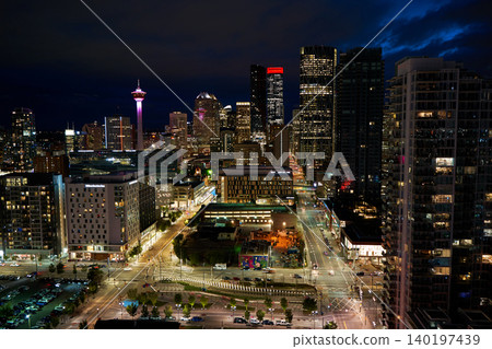 The scene shows Calgary's skyline at night with illuminated buildings and the iconic Calgary Tower. City lights shine against the dark sky. The view captures urban life and architecture The scene shows Calgary's skyline at night with illuminated buildings and the iconic Calgary Tower. City lights shine against the dark sky. The view captures urban life and architecture 140197439