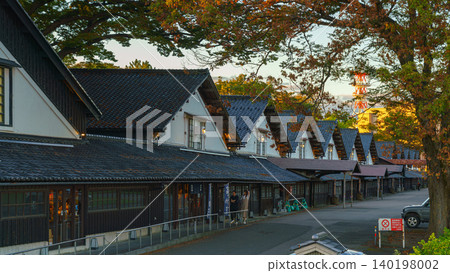 Sakata, Yamagata, Japan - Oct 5 2024, Panoramic view of Sankyo Soko Storehouse with an alley of trees nearby, at sunset, without people, Sakata, Japan 140198002