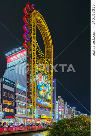 Osaka, Japan - Sep 22 2024, panoramic view from below of Don Quijote Dotonbori shopping and entertainment complex and Ferris wheel, in Dotonbori district, on canal corniche, at nighttime, Osaka, Japan Osaka, Japan - Sep 22 2024, panoramic view from below of Don Quijote Dotonbori shopping and entertainment complex and Ferris wheel, in Dotonbori district, on canal corniche, at nighttime, Osaka, Japan 140198019