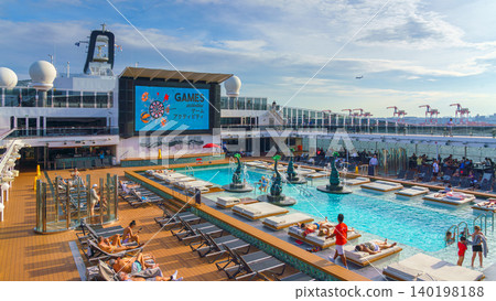 Tokyo, Japan - Oct 2 2024, panoramic view of the public outdoor pool on the upper deck of the MSC Belissima cruise ship, with people relaxing on sun loungers, at daytime, Tokyo, Japan Tokyo, Japan - Oct 2 2024, panoramic view of the public outdoor pool on the upper deck of the MSC Belissima cruise ship, with people relaxing on sun loungers, at daytime, Tokyo, Japan 140198188
