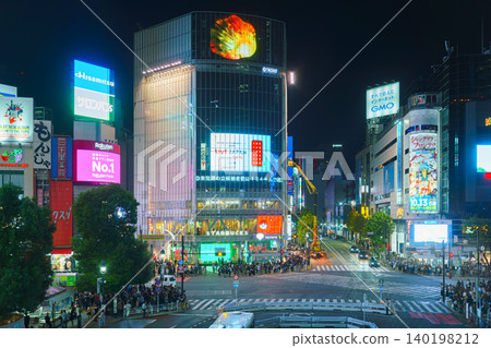 Tokyo, Japan - Oct 15 2024, panoramic aerial view of famous Shibuya intersection with a crowd of people on sidewalk, at night with illumination and advertising on facades of buildings, Tokyo, Japan 140198212