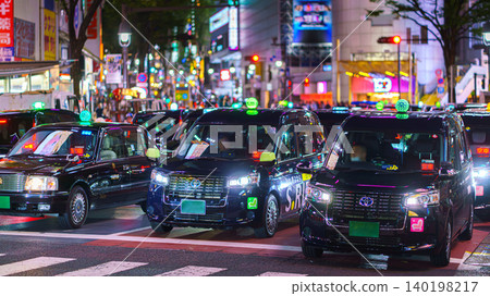 Tokyo, Japan - Oct 15 2024, panoramic view of black cabs of taxis standing at the Shibuya Crossroad at night, on background facades are covered with illuminated advertisement, Tokyo, Japan Tokyo, Japan - Oct 15 2024, panoramic view of black cabs of taxis standing at the Shibuya Crossroad at night, on background facades are covered with illuminated advertisement, Tokyo, Japan 140198217