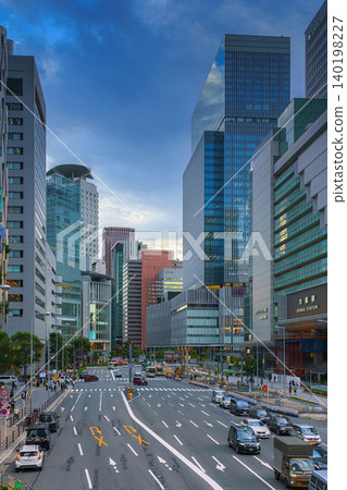 Osaka, Japan - Sep 25 2024, panoramic view of a wide street with cars and buses, trees are planted along road, people walk along sidewalks, a mall in background, at evening, Osaka, Japan Osaka, Japan - Sep 25 2024, panoramic view of a wide street with cars and buses, trees are planted along road, people walk along sidewalks, a mall in background, at evening, Osaka, Japan 140198227