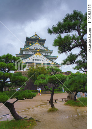 Osaka, Japan - Sep 22 2024, Panoramic view of Osaka Castle among the trees, from behind the fortress wall and the foliage of the trees, on a rainy day, without people, Osaka, Japan Osaka, Japan - Sep 22 2024, Panoramic view of Osaka Castle among the trees, from behind the fortress wall and the foliage of the trees, on a rainy day, without people, Osaka, Japan 140198235