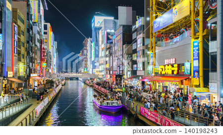 Osaka, Japan - Sep 22 2024, Panoramic view of Dotonbori river with a ship with tourists, a lot of people on embankment, there are a lot of advertising and illuminations on buildings, Osaka, Japan Osaka, Japan - Sep 22 2024, Panoramic view of Dotonbori river with a ship with tourists, a lot of people on embankment, there are a lot of advertising and illuminations on buildings, Osaka, Japan 140198243