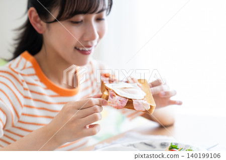 Young woman eating breakfast in the living room 140199106