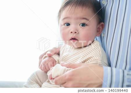 A baby hugged by a father A baby hugged by a father 140199440
