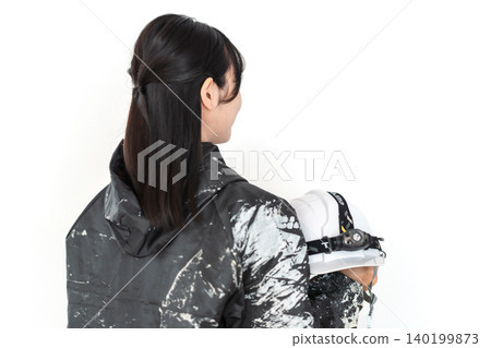 一位面帶微笑的年輕女工,身穿沾滿油漆的工作服,手裡拿著安全帽,背景是白色。 一位面帶微笑的年輕女工,身穿沾滿油漆的工作服,手裡拿著安全帽,背景是白色。 140199873