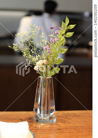 Glass Vase with Delicate Floral Arrangement on Wooden Surface Glass Vase with Delicate Floral Arrangement on Wooden Surface 140200209