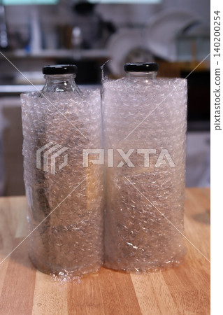 Bottles in Bubble Wrap on Wooden Surface Bottles in Bubble Wrap on Wooden Surface 140200254