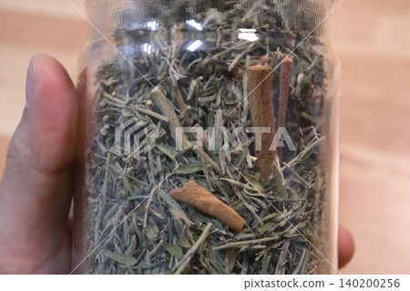 Jar of Dried Herbs and Cinnamon Sticks Held in Hand Jar of Dried Herbs and Cinnamon Sticks Held in Hand 140200256