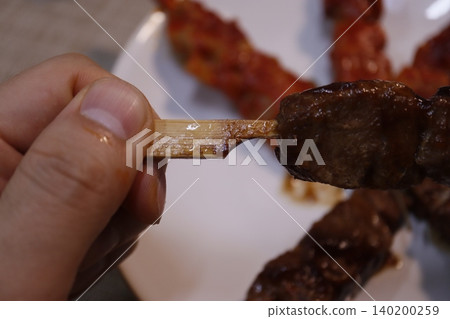 Grilled Meat Skewer Held by Hand Close-Up Grilled Meat Skewer Held by Hand Close-Up 140200259