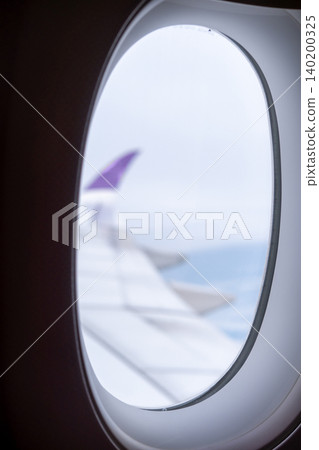 Sky and cloud seen through the window of airplane, with the plane wing Sky and cloud seen through the window of airplane, with the plane wing 140200325