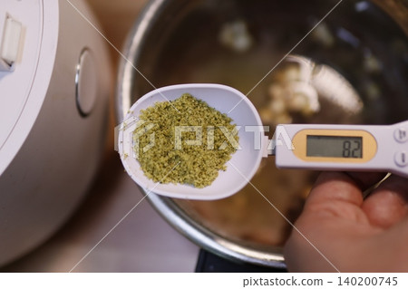 Measuring Herbs with Digital Scale in Kitchen Measuring Herbs with Digital Scale in Kitchen 140200745