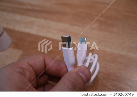 Hand Holding USB and USB-C Cables Close-Up Hand Holding USB and USB-C Cables Close-Up 140200749
