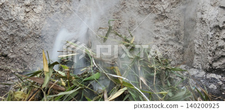 A close-up photo shows white smoke billowing from a pile of dry grass, leaves and plant debris being burned near a concrete wall. A close-up photo shows white smoke billowing from a pile of dry grass, leaves and plant debris being burned near a concrete wall. 140200925