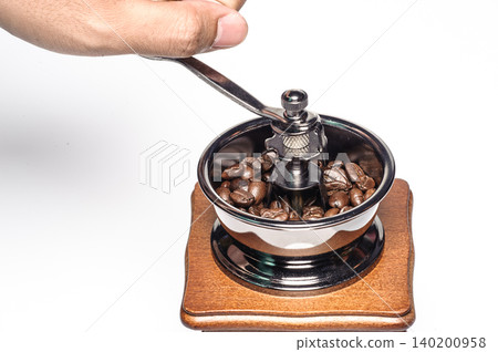 a hand holding handle of the grinding machine  coffee with coffee beans from on white background 140200958