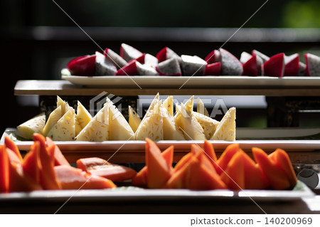 sliced tropical fruit such as pineapple, dragonfruit, and ripe papaya served in restaurant sliced tropical fruit such as pineapple, dragonfruit, and ripe papaya served in restaurant 140200969