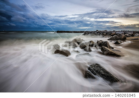 beautiful twilight colorful vivd blue and oranges graduated sky and sea behind rocky shore beautiful twilight colorful vivd blue and oranges graduated sky and sea behind rocky shore 140201045