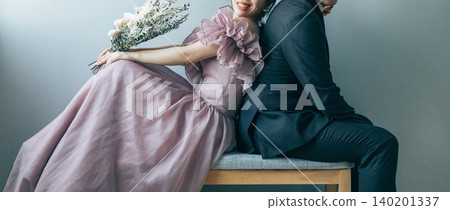 新郎新娘背靠背坐在椅子上拍攝婚前照。 140201337