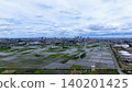 Aerial view of rice paddies and skyscrapers in the suburbs of a city, under a dynamic sky. 140201425
