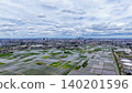 A panoramic view of vast rice paddies and cities stretching out beneath dynamic clouds. 140201596