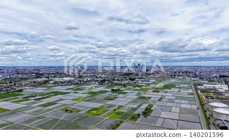 A panoramic view of vast rice paddies and cities stretching out beneath dynamic clouds. A panoramic view of vast rice paddies and cities stretching out beneath dynamic clouds. 140201596