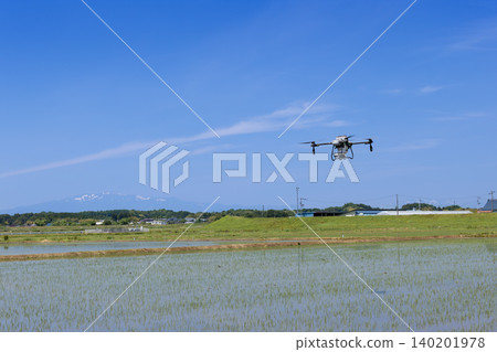 無人機在稻田和白雪皚皚的栗駒山上噴灑除草劑。 無人機在稻田和白雪皚皚的栗駒山上噴灑除草劑。 140201978